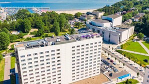 Un grand hôtel à plusieurs étages, doté d’un parking et offrant une vue sur la plage et la mer.