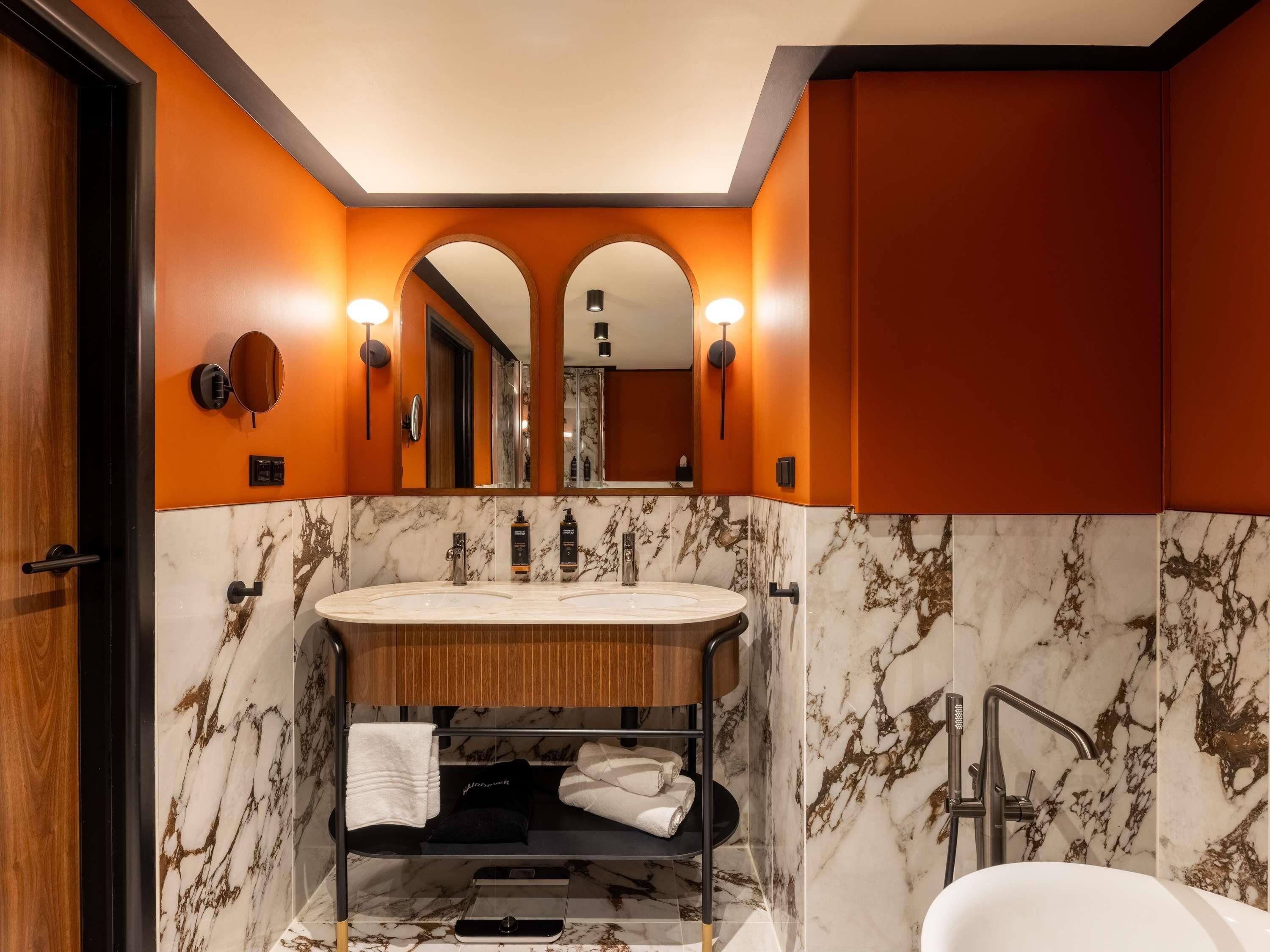 A modern bathroom with a marble vanity, a large mirror, and a separate shower area.