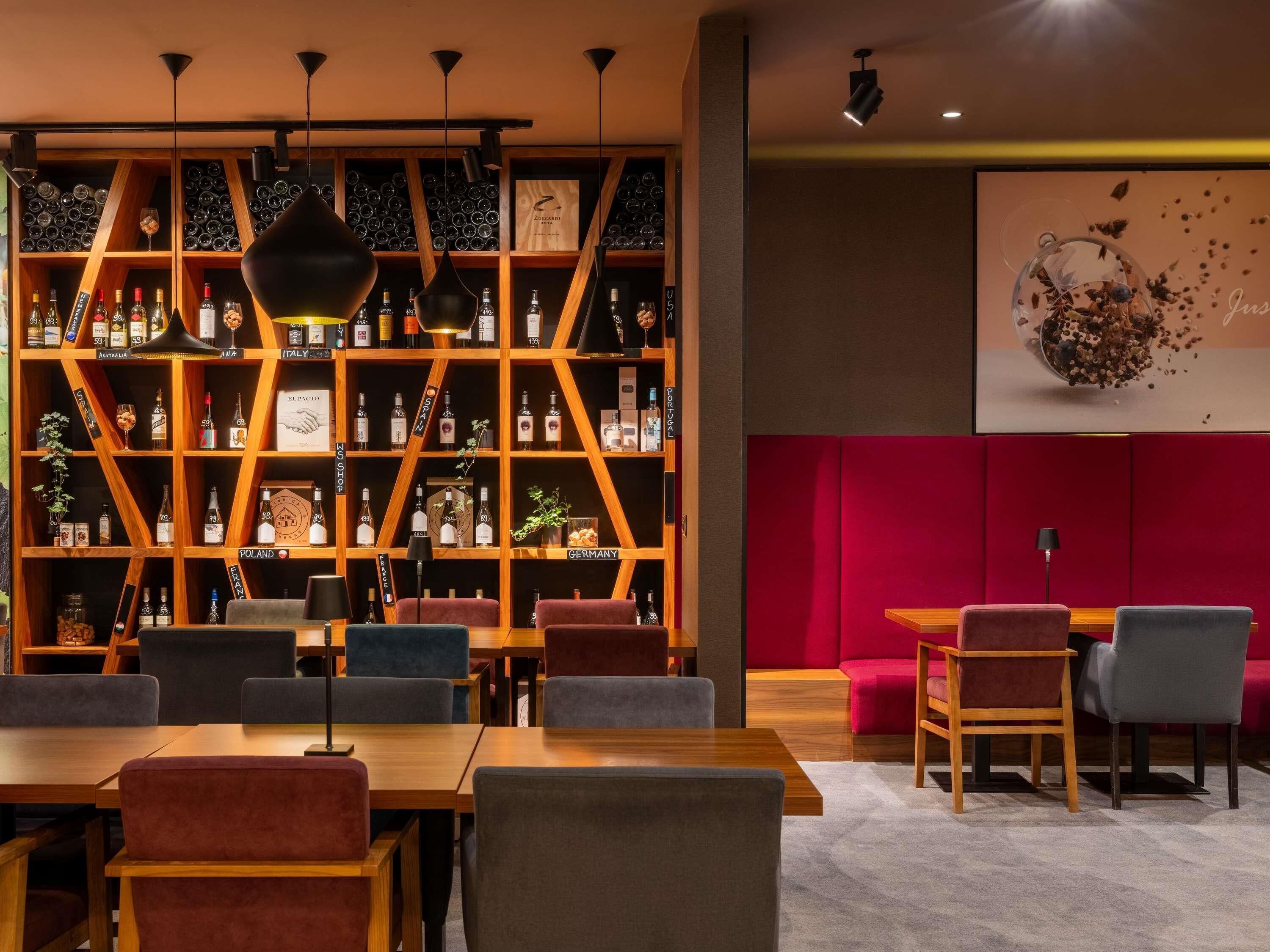 Een bar met een wijn- en drankenkast, zitplaatsen en een rode accentmuur.