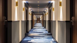 Un long couloir étroit, doté d’un tapis à motifs et d’un éclairage fixé au mur.