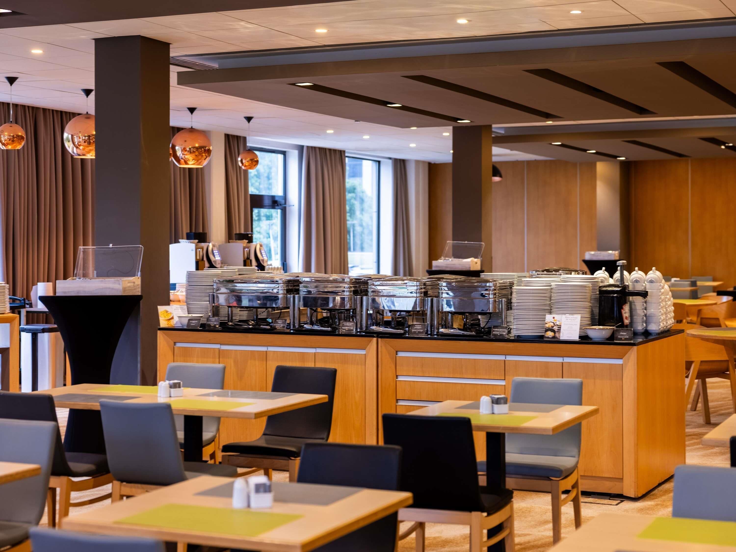 A modern cafe with a buffet counter, seating area, and large windows.