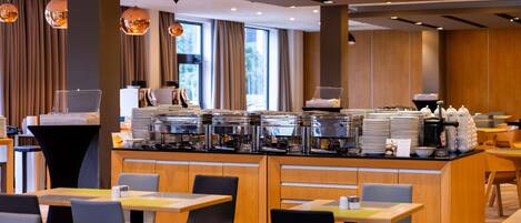 Una cafetería moderna con mostrador de buffet, zona de estar y grandes ventanales.