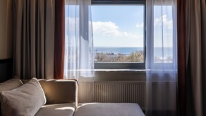 Une chambre d’hôtel avec un lit, une fenêtre avec des rideaux et une vue sur la mer.