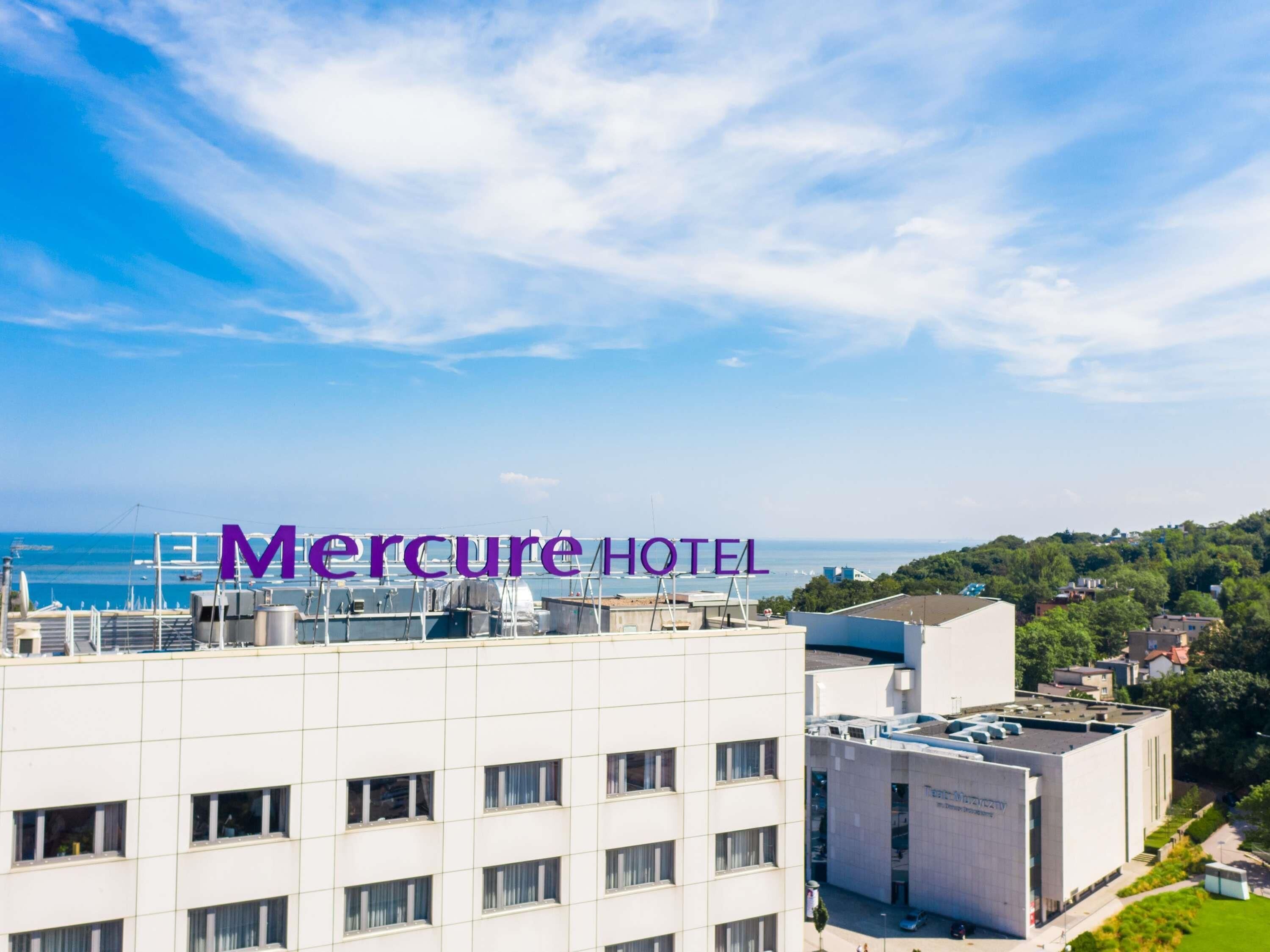 A hotel building with a view of the sea and a clear sky.