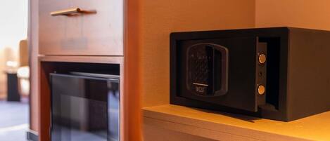 A microwave on a wooden shelf in a kitchen area with a refrigerator below.