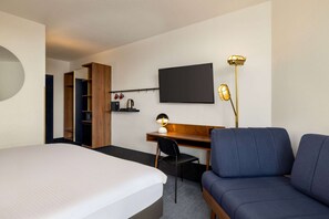 A hotel room with a bed, a desk with a chair, a TV, a lamp, and a wardrobe. - Vienna House by Wyndham Amber Baltic Miedzyzdroje (Miedzyzdroje)