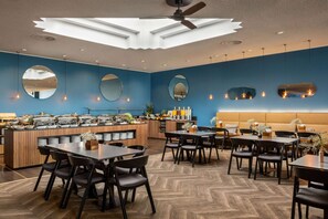 A modern restaurant with a central bar area, multiple dining tables, and a herringbone patterned floor. - Vienna House by Wyndham Amber Baltic Miedzyzdroje (Miedzyzdroje)