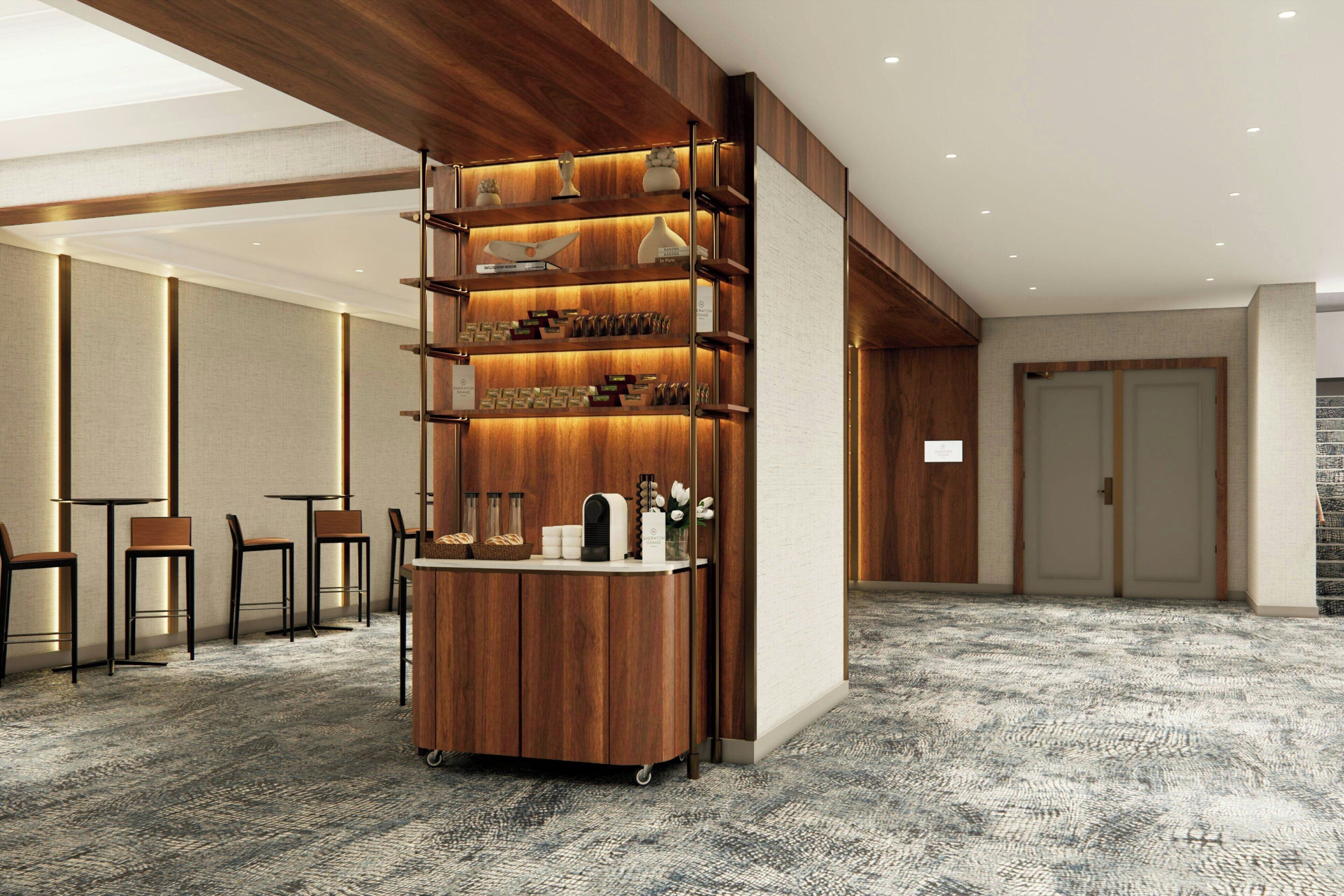 Un vestíbulo de hotel con un mostrador de recepción de madera, zona de estar y piso alfombrado.