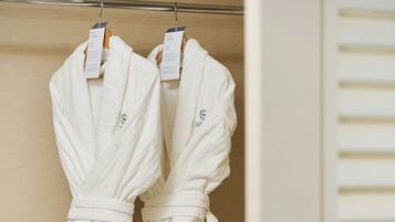 A closet with two white robes hanging on a rod.