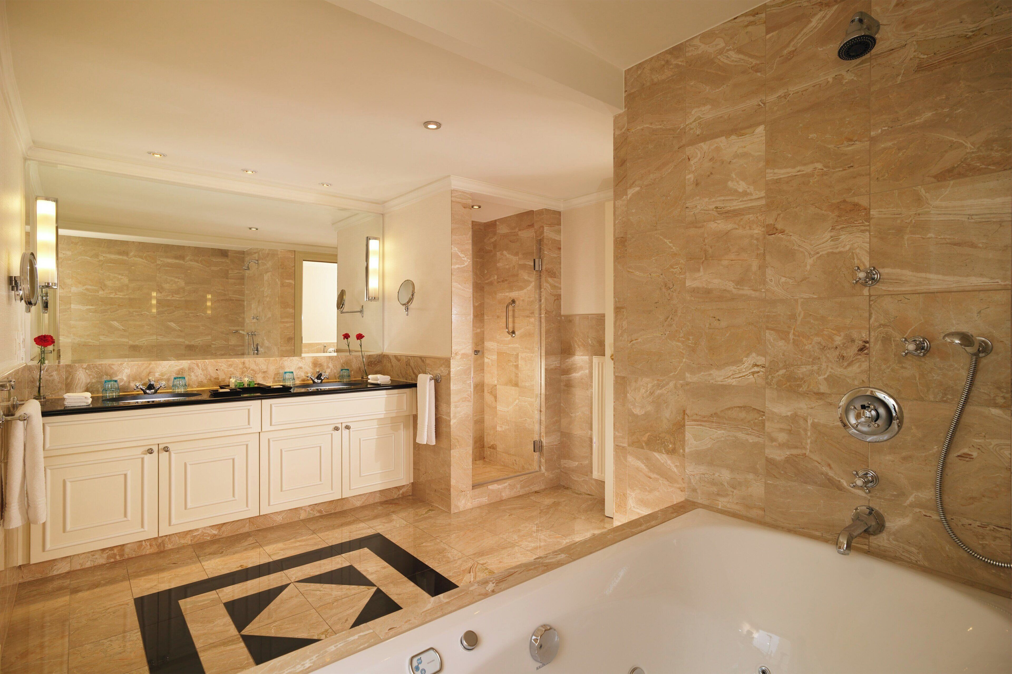 A bathroom with a bathtub, a shower, a vanity with a mirror, and a tiled floor.