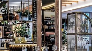 Un interior de restaurante moderno con una zona de bar, asientos y una exhibición de plantas y equipos de cocina.