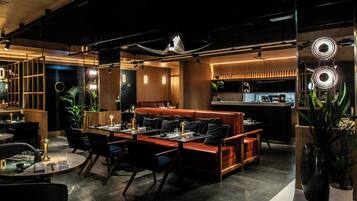 Un restaurante moderno con barra, mesas y una cocina visible al fondo.