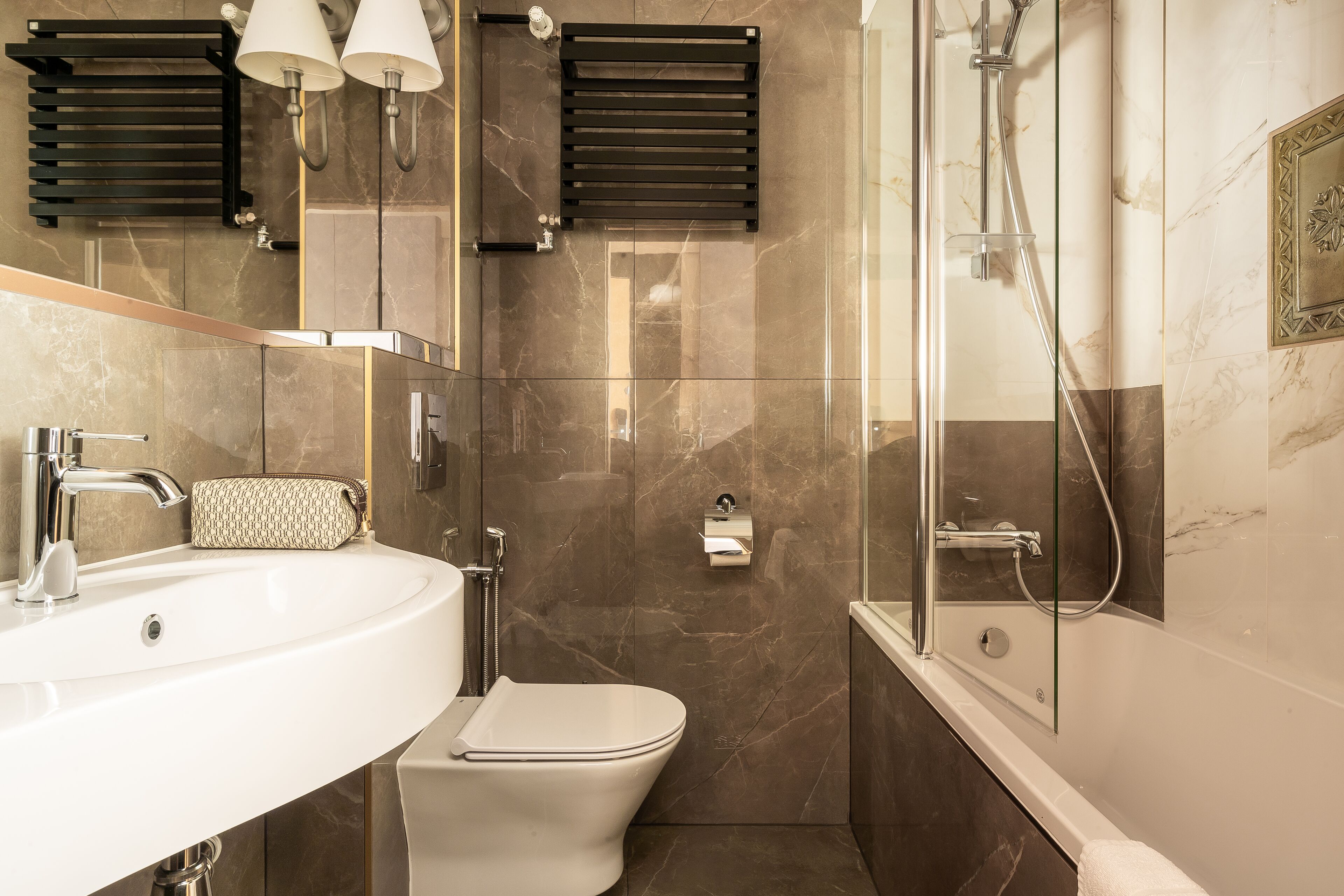 A modern bathroom with a white sink, toilet, and glass-enclosed shower.