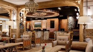 A lobby with wooden furniture, a fireplace, and a large chandelier.