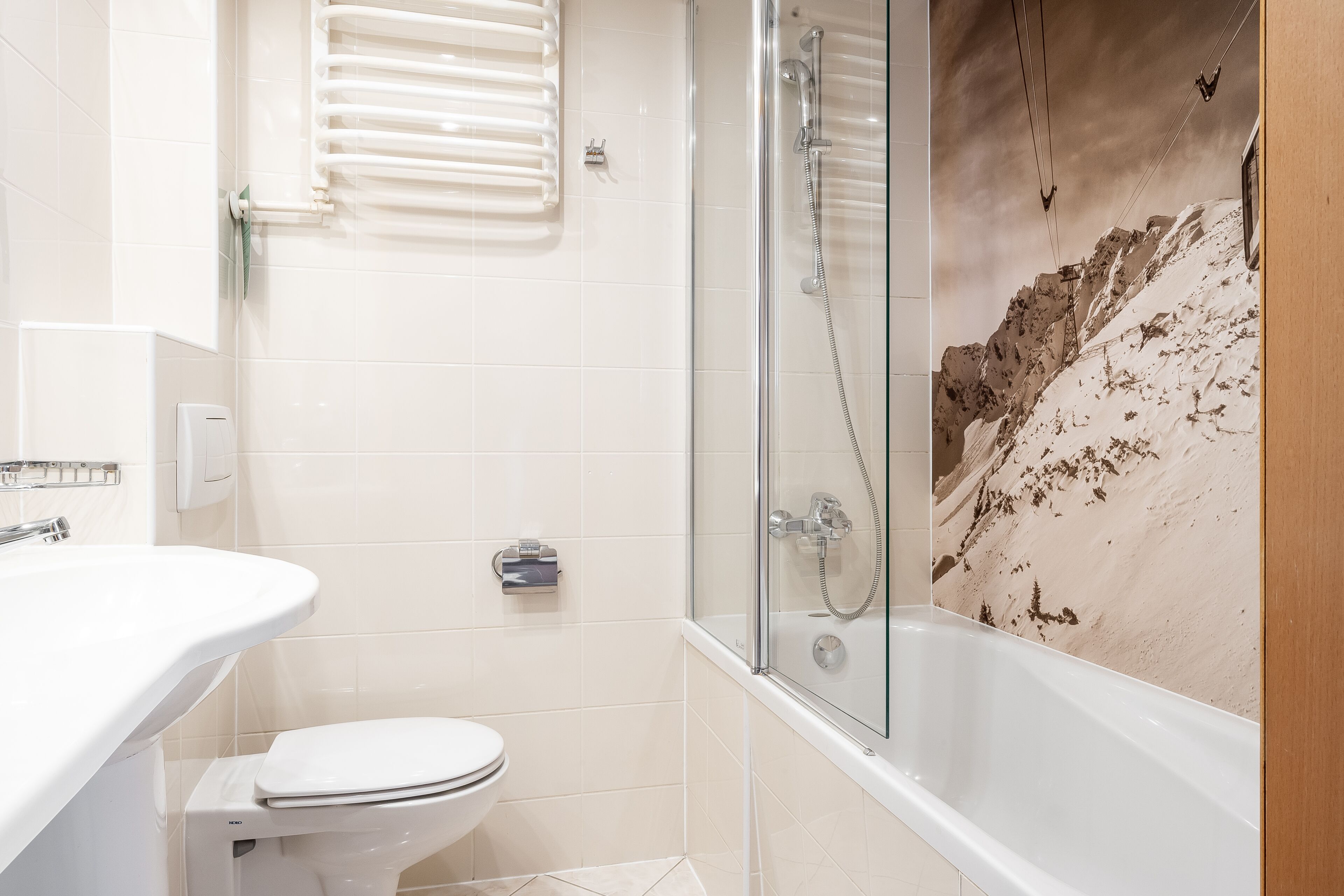 A bathroom with a glass-enclosed shower, a white sink, and a toilet.