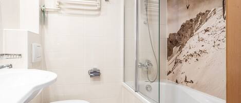 A bathroom with a glass-enclosed shower, a white sink, and a toilet.