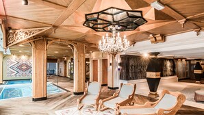 Eine großzügige Lobby mit Schwimmbad, Holzmöbeln und einem Chandelier.