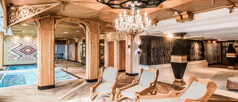 A spacious lobby with a pool, wooden furniture, and a chandelier.