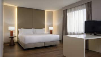 A modern hotel room with a bed, bedside lamps, a TV, and a desk.