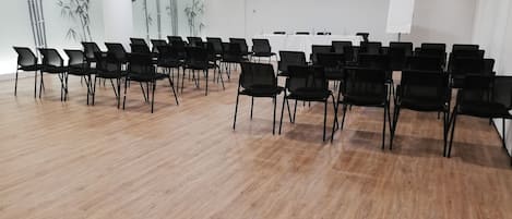 A conference room with rows of black chairs, a whiteboard, and a bamboo-themed wall.