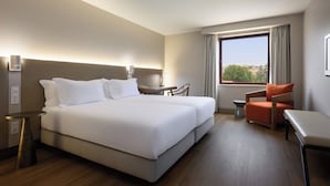 Habitación de hotel con una cama grande, un escritorio, una silla y vistas al exterior.