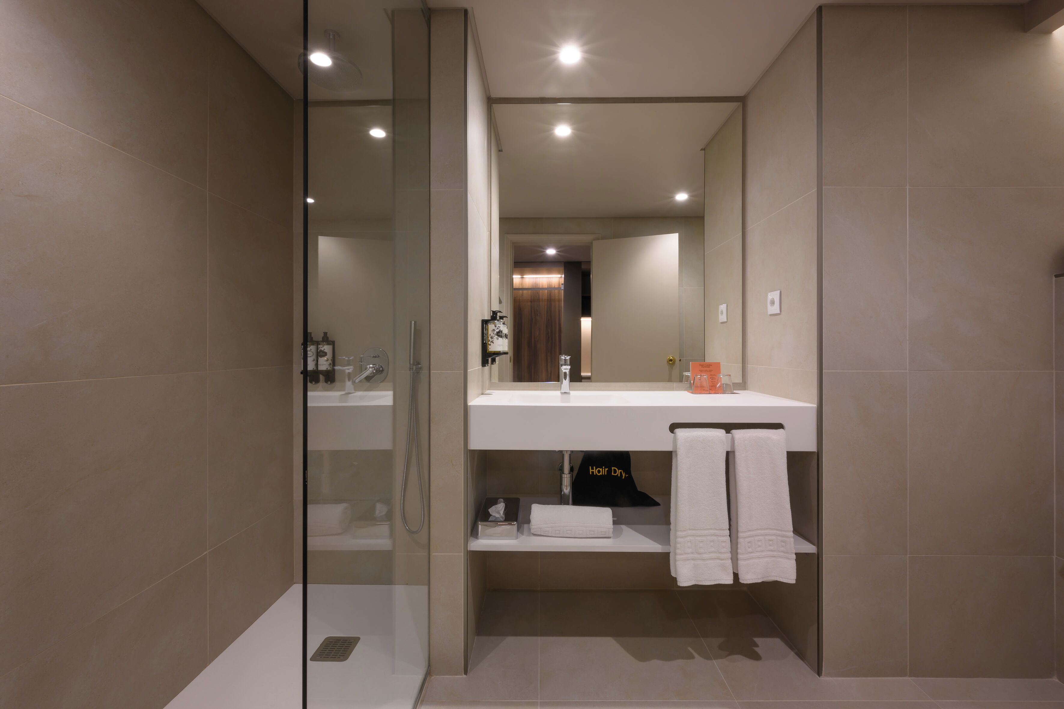A modern bathroom with a glass shower enclosure, a white sink, and a mirror above it.