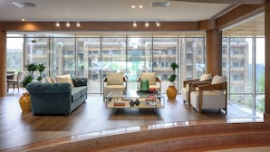 Amplia sala de estar con un sofá, sillones y una mesa de centro, ventanas grandes que ofrecen vistas de la ciudad.