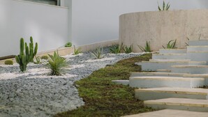 A modern outdoor pathway with steps leading to a building, surrounded by various plants and a white wall. - HF Fénix Lisboa (Lisbon)