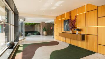 Un hall d’entrée moderne avec un tapis aux motifs courbes, un comptoir d’accueil et une grande plante.