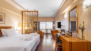 A hotel room with a bed, a desk, a chair, a TV, and a mirror.