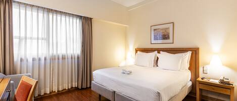 A hotel room with a bed, a desk, and a chair.