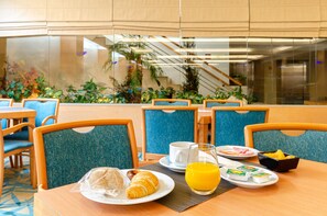 A breakfast setting with a plate of croissants, orange juice, and a bowl of fruit.