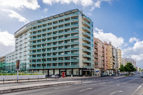A multi-story hotel with a modern design, featuring balconies on each floor and a prominent entrance.