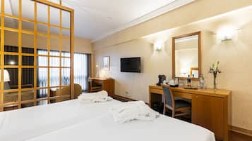 Habitación de hotel con una cama grande, un escritorio con silla, televisión y espejo.