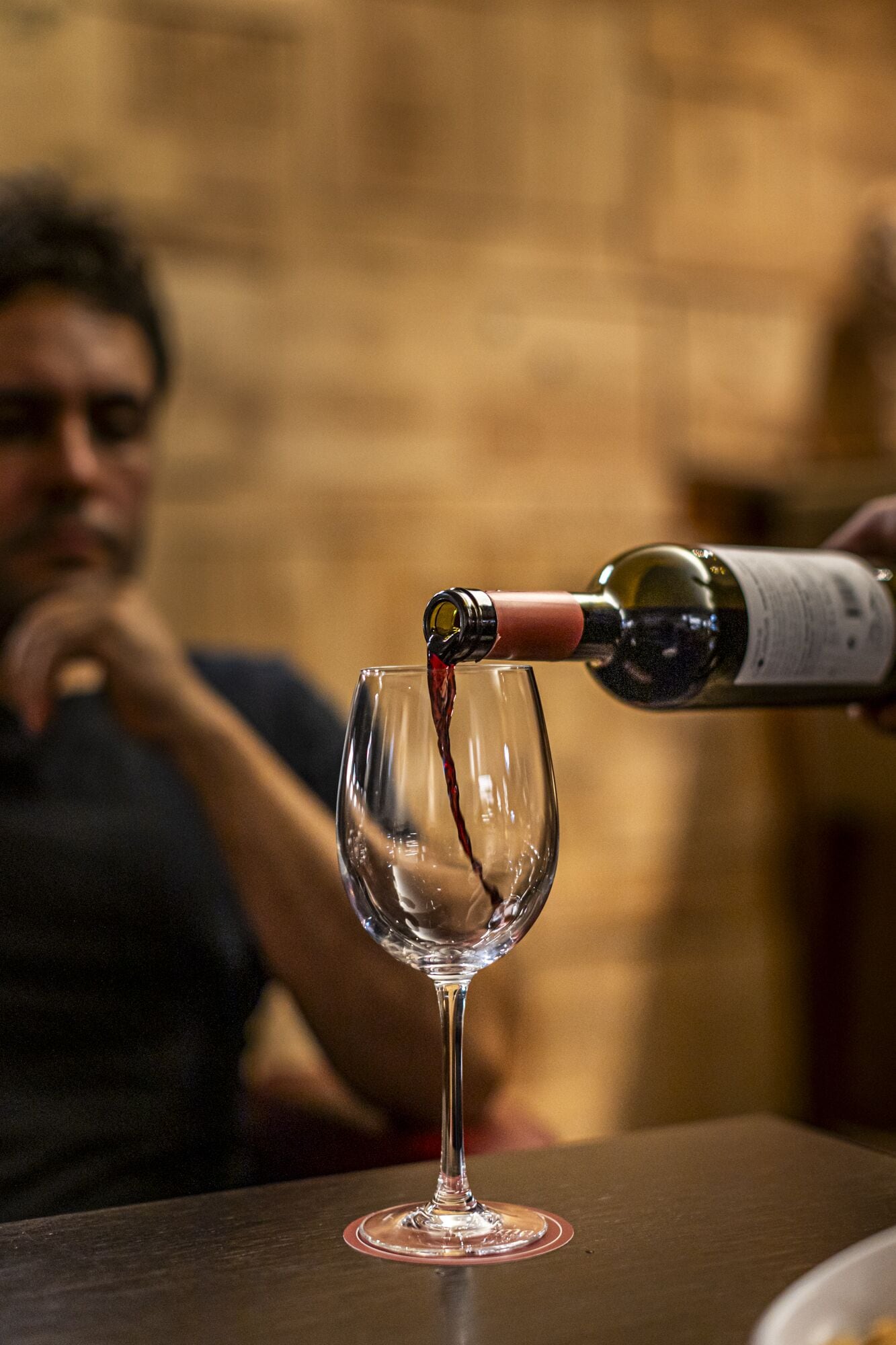 A wine bottle being poured into a clear wine glass.