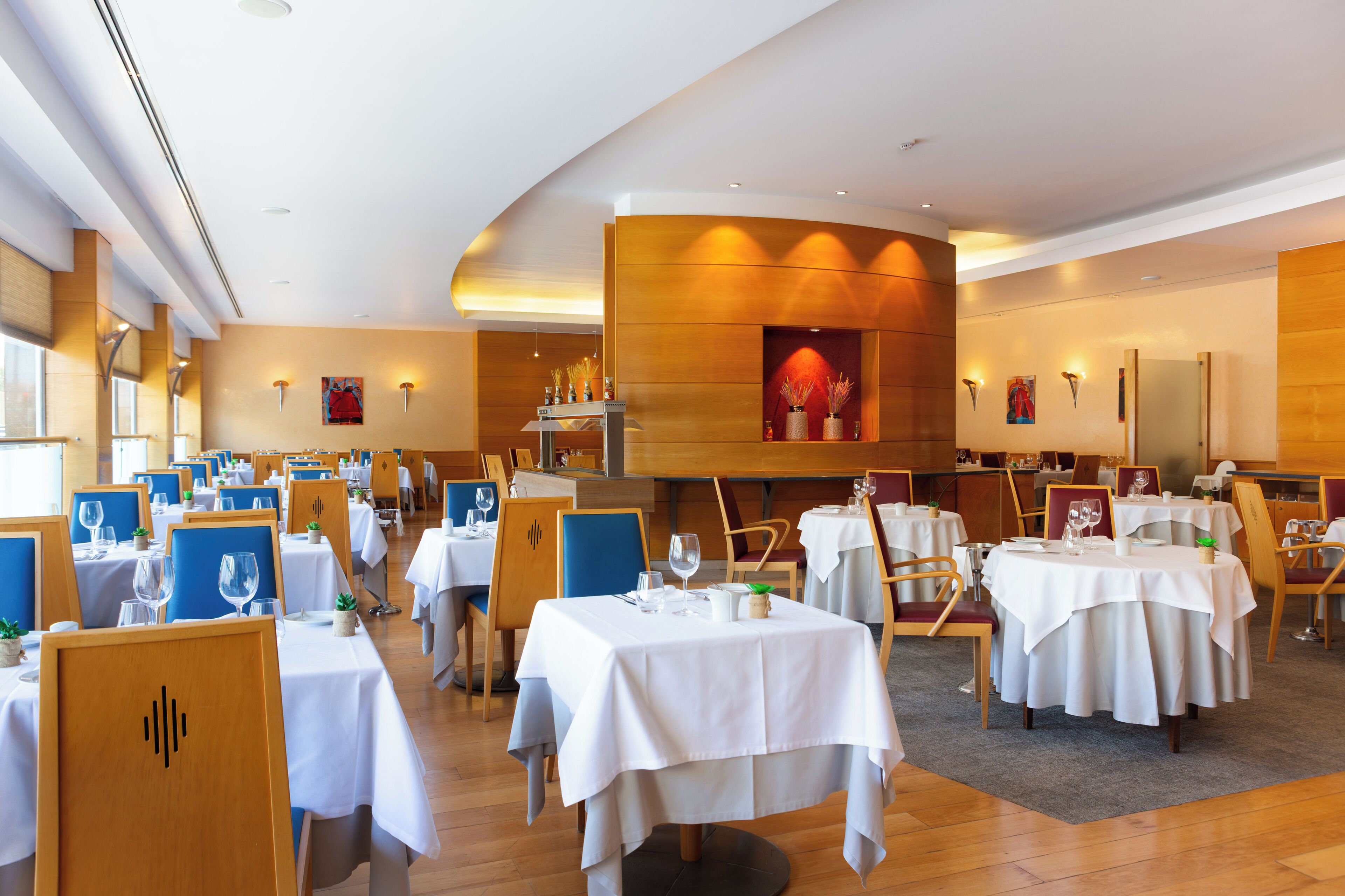 Ein Restaurant mit mehreren Tischen, Stühlen und einer dekorativen Wand in der Mitte.