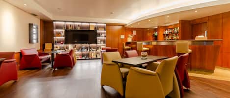 Un moderno vestíbulo de hotel con zona de bar, asientos y un televisor de pantalla plana.
