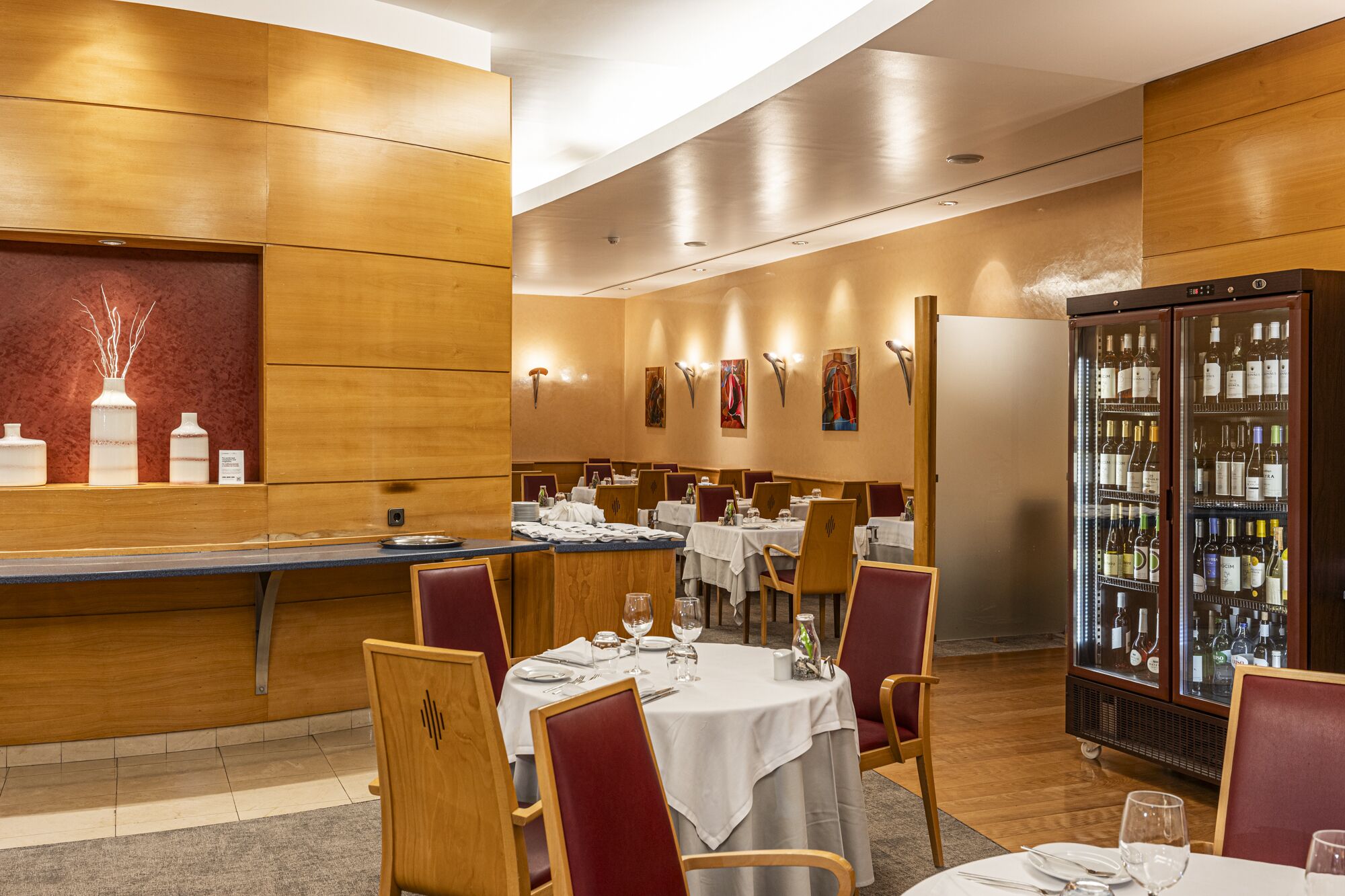 Un restaurante con paredes de paneles de madera, manteles blancos y sillas rojas.