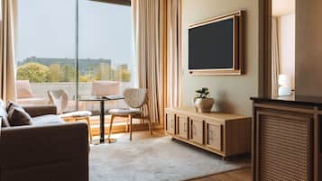 Une chambre d’hôtel moderne dotée d’une grande fenêtre, d’un téléviseur à écran plat, d’un canapé, d’une table à manger et d’un meuble de rangement.