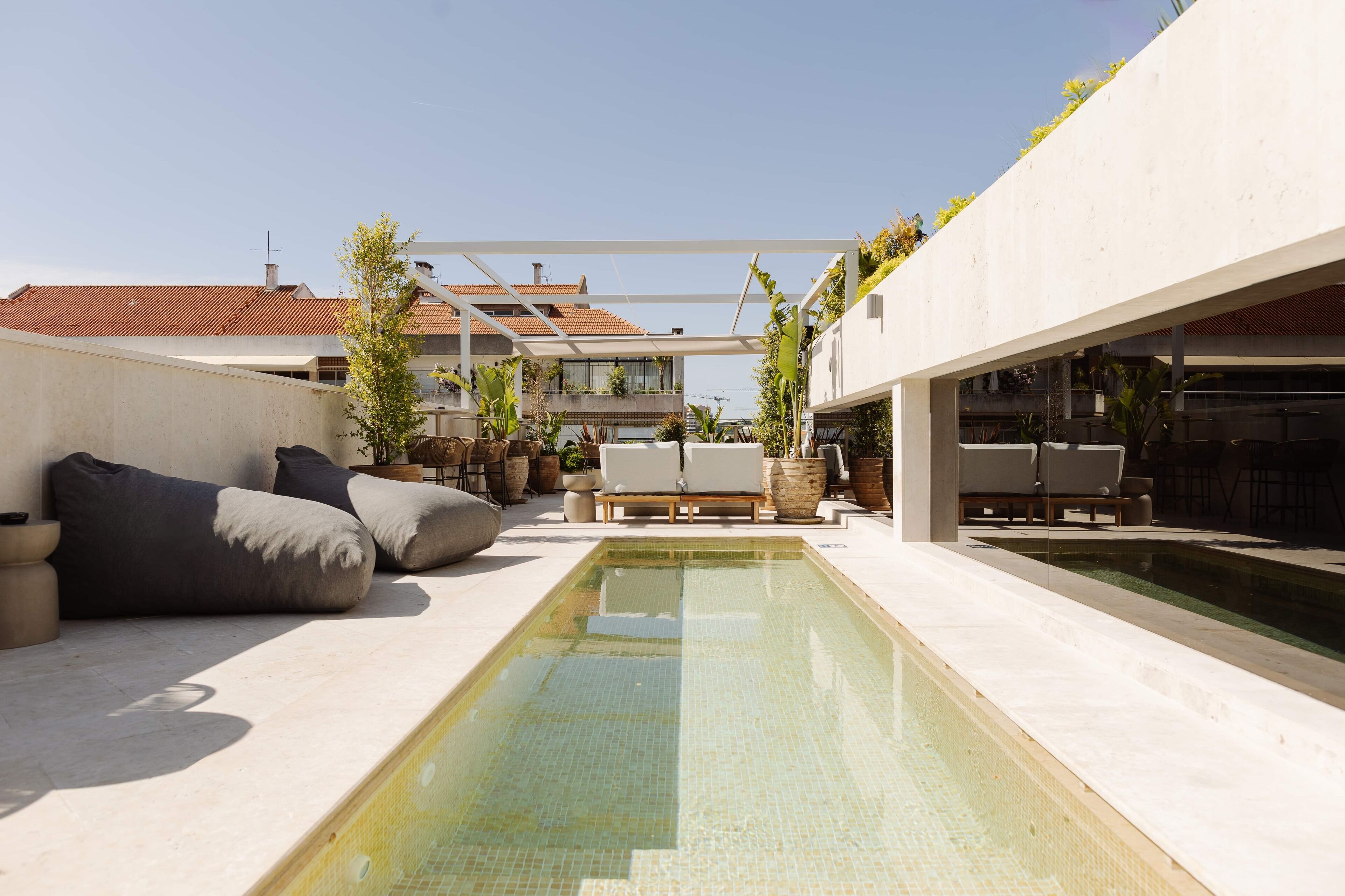 A modern outdoor pool area with a rectangular pool, lounge chairs, and potted plants.