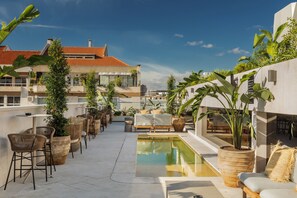 Eine Dachterrasse mit Pool, Sitzbereichen und Topfpflanzen.