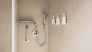 Un baño moderno con ducha, barra de apoyo y tres botellas de champú y acondicionador.
