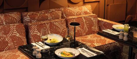 A dining area with patterned sofas, a table set with plates, glasses, and a lamp.