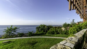 Vista costera con muro de piedra y vegetación, con vista al mar.