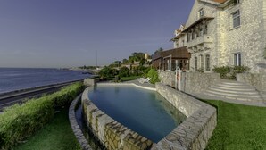 Un edificio de piedra con piscina y vistas al mar.