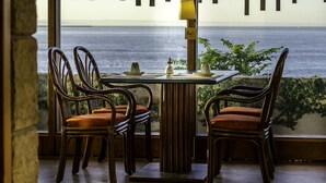 Un comedor con una mesa, sillas, una lámpara y vista al mar.
