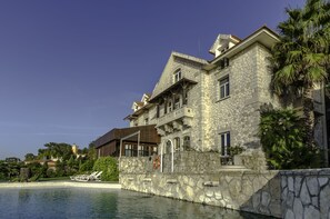 Un gran edificio de piedra con piscina, un flotador y una palmera.