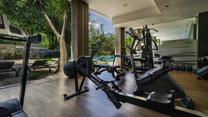 A modern gym with various exercise equipment, large windows, and a view of a swimming pool.
