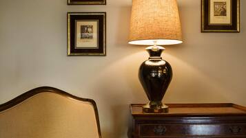 Ein Zimmer mit Lampe, ein Sessel mit Karokissen und gerahmten Bildern an der Wand.