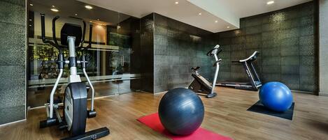 A modern gym with exercise equipment, a large exercise ball, and a red mat.